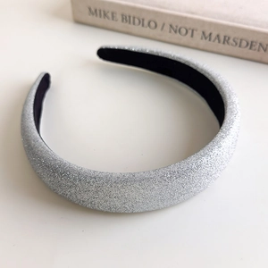 Macro shot of silver glitter headband with black fabric lining on a book background