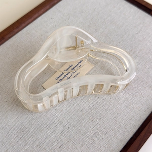 Detail showing marble texture and metallic spring on the cream wavy hair claw clip