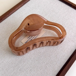 Close-up of a translucent brown acrylic hair claw clip with a hollow wave design