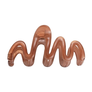 Macro detail of wave shaped translucent brown resin hair claw clip for secure hairstyling