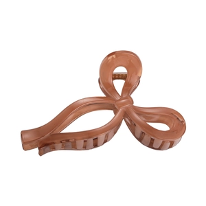 Detail of amber brown bow hair claw clip made of translucent resin with metal spring