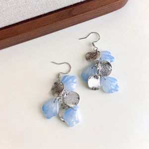 Detail view of light blue petal earrings with silver hammered metal disks and ear hooks