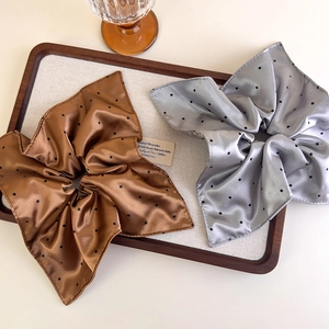 Detailed close-up of brown and silver satin polka dot scrunchies on a wooden display tray