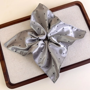 Detail of silver grey satin hair scrunchie with black polka dots and pleated petal shape