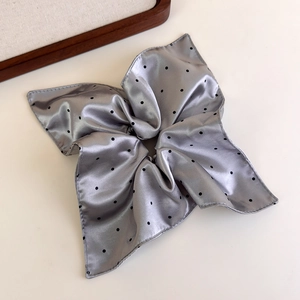 Detailed view of large grey satin polka dot scrunchie with elegant pleated fabric texture