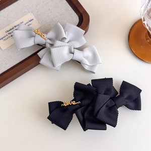 Elegant pair of grey and black bow hair clips with golden love lettering for women