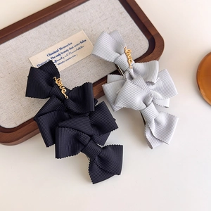 Close-up of handmade ribbed bow hair clips with gold Love charms on a wooden tray