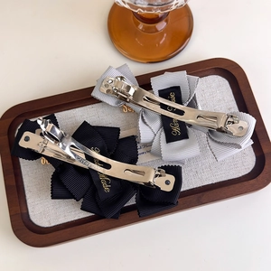 Detail of grey and black handmade ribbon bow hair clips with metal spring fasteners
