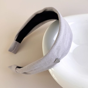 Detail of light grey cotton headband with silver heart charm on white porcelain edge