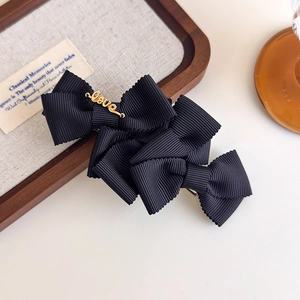 Detailed macro of black ribbed ribbon bow hair clip with golden Love metal accent