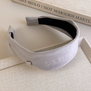 Detail of light gray wide fabric headband featuring a small silver heart-shaped pendant