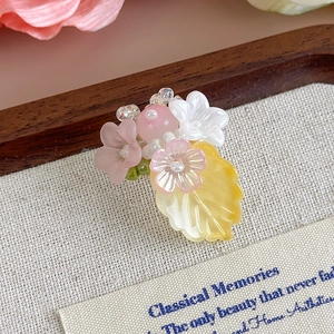 Dettaglio di ciondolo per scarpe fai da te con fiori rosa e crema e foglie gialle