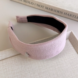 Detail of pink woven cotton headband with a silver heart pendant on a tray