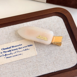 Macro shot of marble textured acetate hair clip featuring gold metal lettering detail
