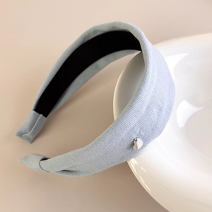 Detailed shot of light blue knitted headband with a small silver heart pendant