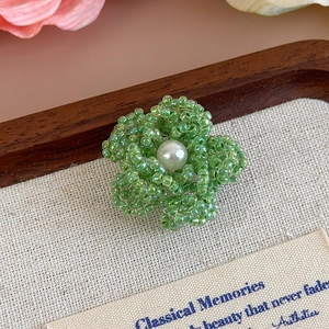 Dettaglio del fiore fatto a mano con perline verdi e perla centrale per decoro DIY