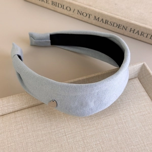 Detail of light blue knitted headband with a delicate silver heart pendant on a wide band