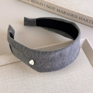 Detail of grey cotton headband featuring a small silver heart charm on a textured tray