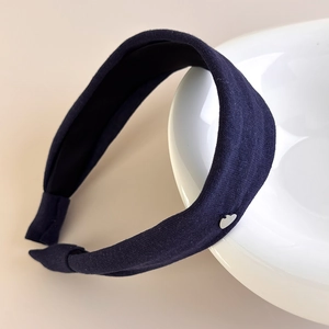 Detailed close-up of dark blue ribbed knit headband featuring a silver heart metal ornament