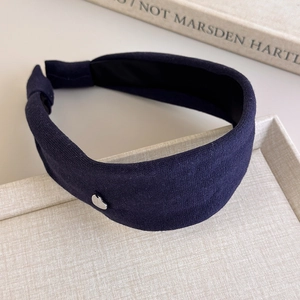 Detail of dark blue knitted headband with metallic silver heart on a textured display