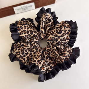 French vintage leopard print satin scrunchie with black ruffled edges on desk