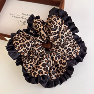 Detail of leopard print fabric scrunchie with black satin pleated edge and soft texture
