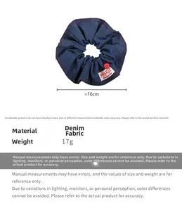 Detail view of blue denim scrunchie with red stitching and 'Have a nice day' label