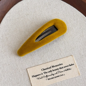 Détail d'une barrette en velours jaune montrant la texture douce et le fermoir métallique