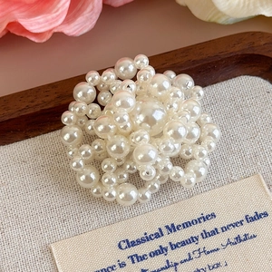 Dettaglio di elegante spilla a fiore con perle bianche su lino con decoro floreale rosa