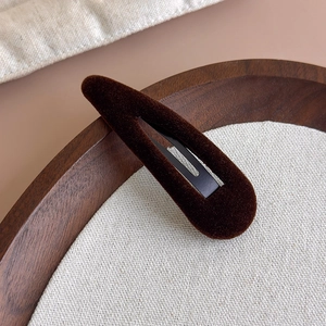 Détail de la pince à cheveux en velours marron foncé sur tissu en lin et plateau