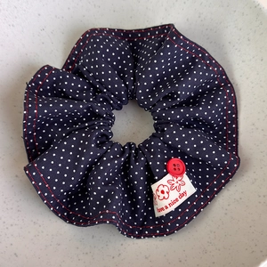Detail of blue polka dot denim scrunchie with red button and fabric label tag