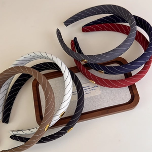 Serre-tête en tissu rayé avec bouton doré logo en plusieurs couleurs sur plateau bois