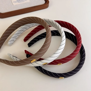 Détail de l'étiquette dorée faite main sur des serre-têtes en tissu rayé en quatre couleurs