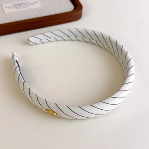 Détail du serre-tête en tissu rayé blanc avec plaque logo dorée Hand Made