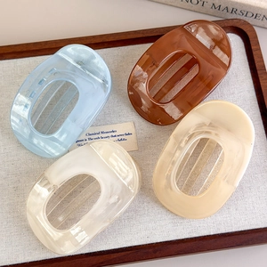 Flat lay of macaron acetate hair clips in a wooden tray with marble and amber colors