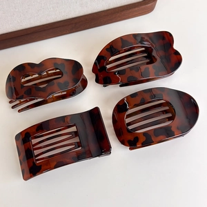 Detail view of leopard print hair claws with multiple geometric shapes on white surface