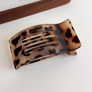 Close-up of tortoise shell leopard hair claw clip showing amber resin texture and teeth