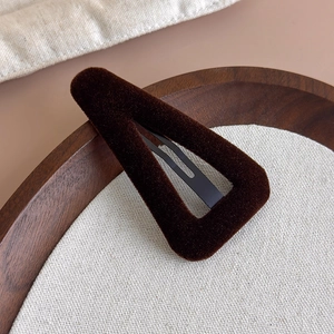Gros plan sur la barrette triangle en velours marron foncé montrant la texture délicate