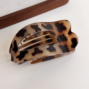 Macro detail of tortoiseshell PC hair claw clip featuring elegant wavy curves and teeth