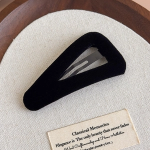 Détail d'une pince à cheveux vintage en velours noir sur un fond en lin minimaliste
