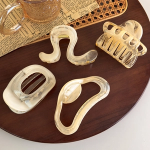 Elegant set of 4 amber and cream geometric hair clips with marble texture on wooden tray