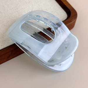 Detail of light blue macaron hair claw clip with marble texture in a wooden tray