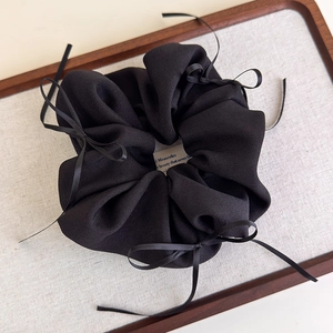 Eleganter schwarzer Haargummi aus strukturiertem Stoff mit zarten Schleifendetails
