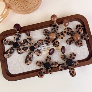 Retro leopard print flower stud earrings with gold accents in a wooden display tray
