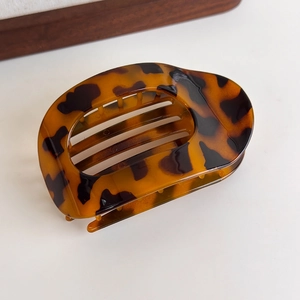 Macro detail of leopard print hair claw with smooth amber texture and hollowed design