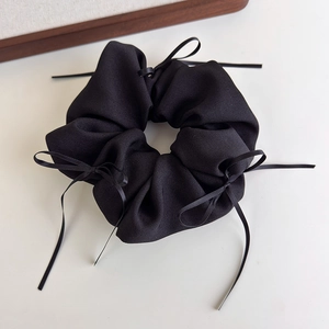 Detailansicht eines schwarzen gerippten Scrunchie mit eleganten kleinen Bandschleifen