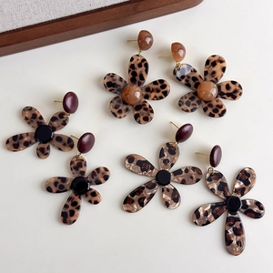 Detailed close-up of leopard print flower earrings in three elegant color variations