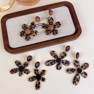 Set of three leopard print flower stud earrings with gold accents on a vintage tray