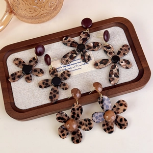 Detailed view of leopard print flower earrings on a textured tray showing resin textures