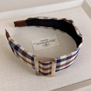 Detail of vintage checkered wide headband with square buckle on a linen display